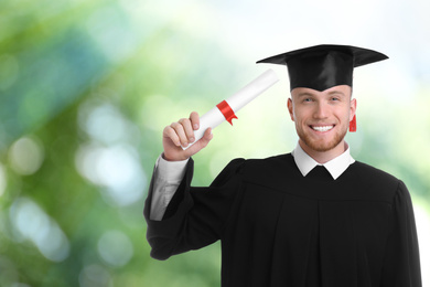 Image of Happy student with graduation hat and diploma on blurred background, space for text