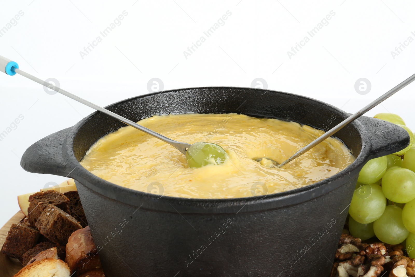 Photo of Dipping grapes into fondue pot with tasty melted cheese isolated on white