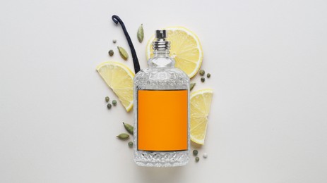 Photo of Bottle of perfume, lemon slices and cardamom on light grey background, top view