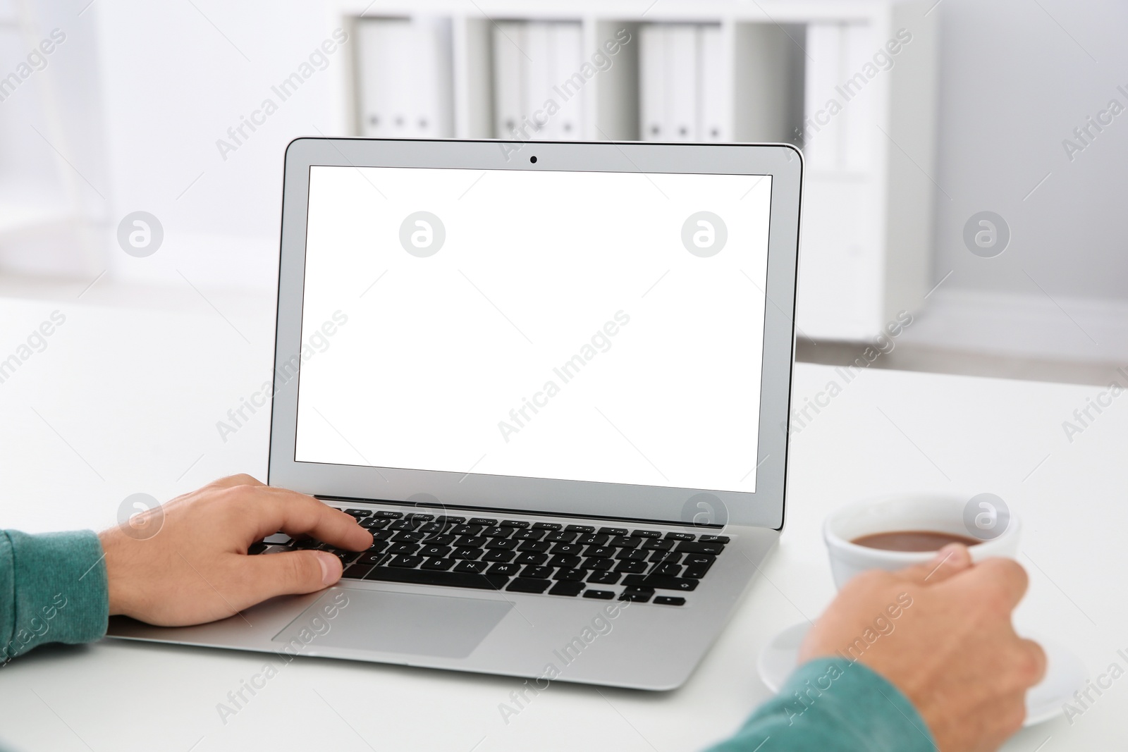 Photo of Young man working with modern laptop at table, closeup. Mockup for design