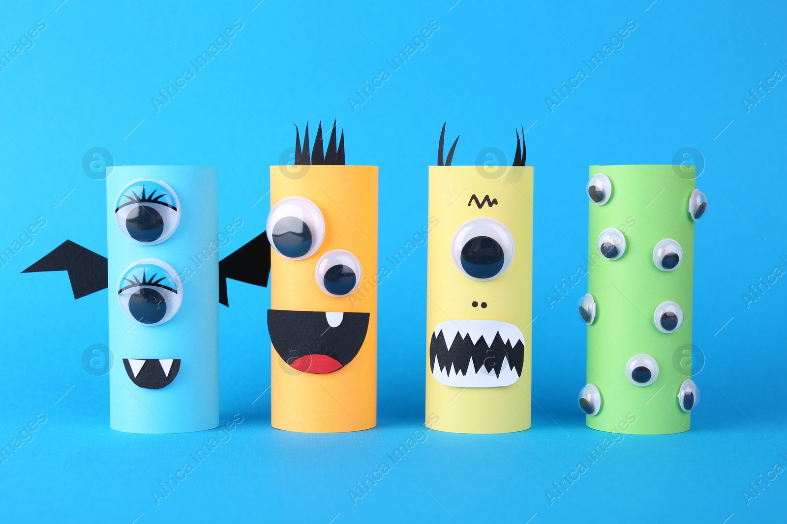 Photo of Spooky paper monsters on light blue background. Halloween decoration