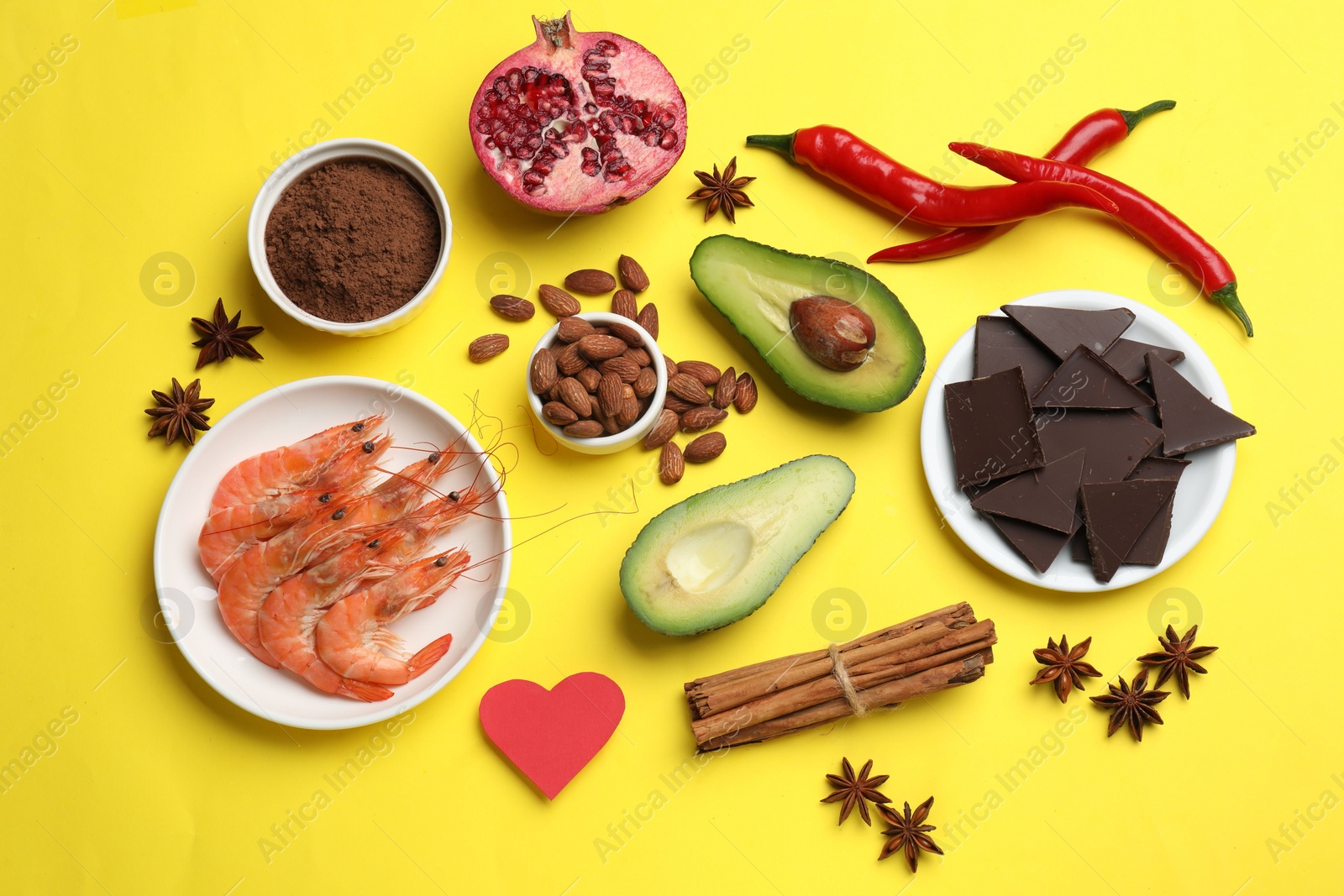 Photo of Natural aphrodisiac. Different products and paper heart on yellow background, flat lay