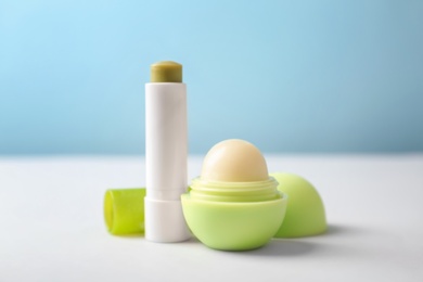 Hygienic lipstick and balm on table against color background