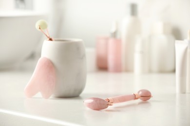 Photo of Natural face rollers and gua sha tool on counter in bathroom