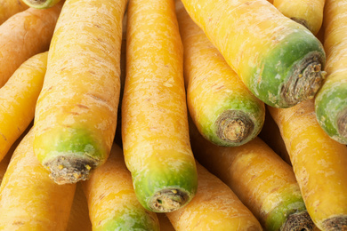 Photo of Fresh raw yellow carrots as background, closeup