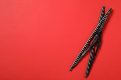 Photo of Car windshield wipers on red background, flat lay. Space for text