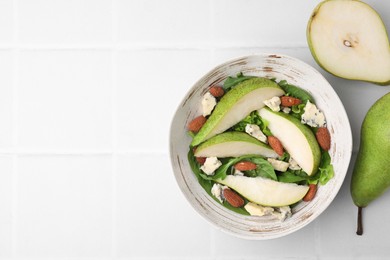 Photo of Delicious pear salad in bowl and fruits on light tiled table, top view. Space for text