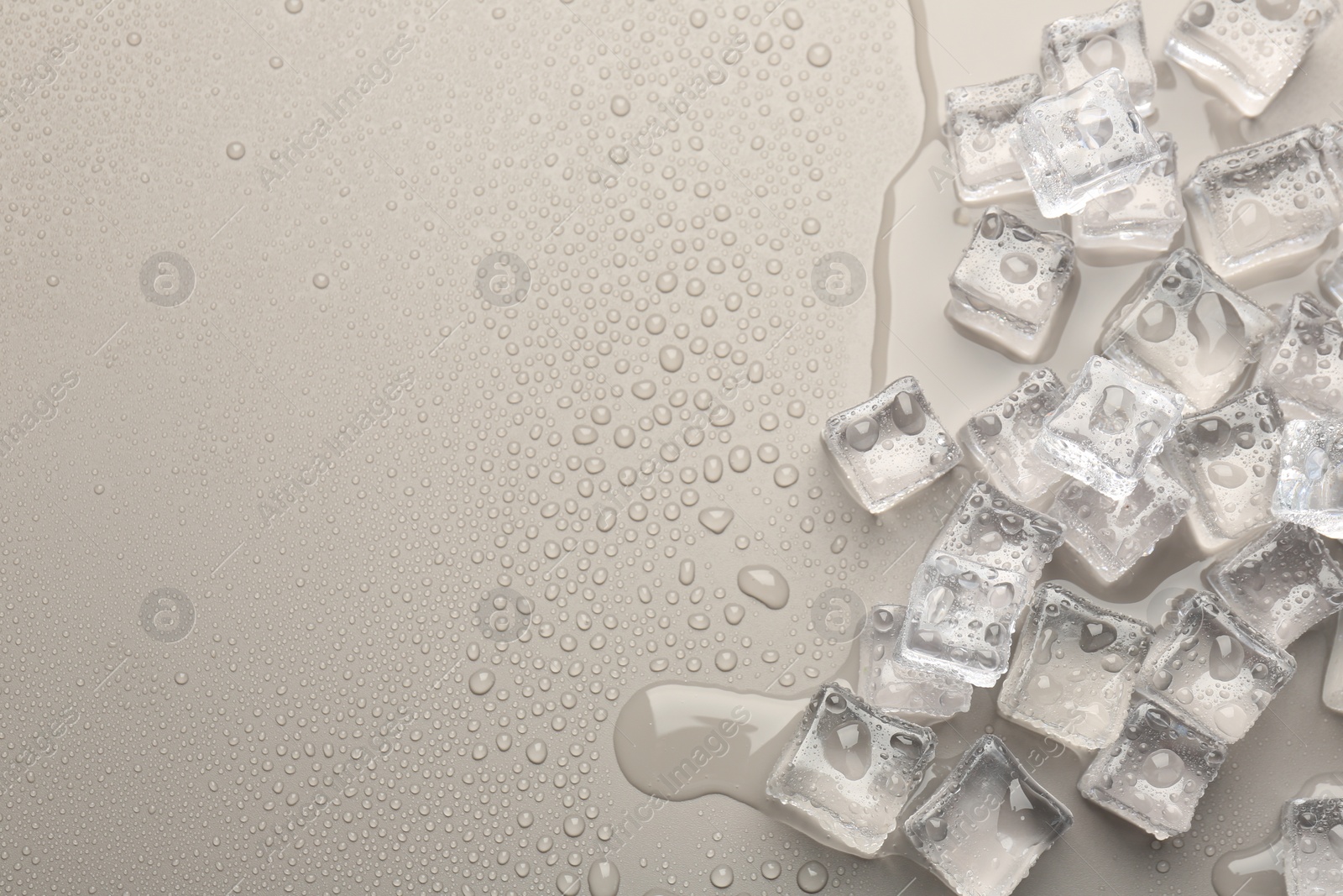 Photo of Melting ice cubes and water drops on light grey background, flat lay. Space for text