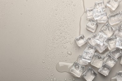 Melting ice cubes and water drops on light grey background, flat lay. Space for text
