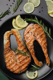 Photo of Plate with tasty salmon steaks on black table, flat lay