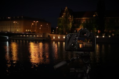 Taking photo of beautiful cityscape at night with camera mounted on tripod
