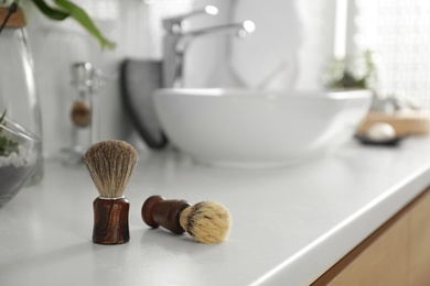 Shaving brushes on light countertop in bathroom
