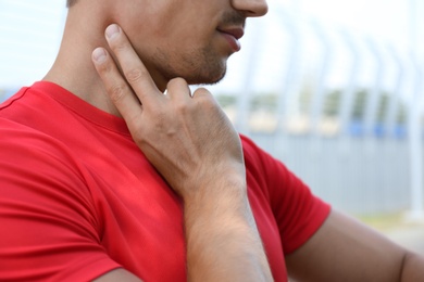 Young man checking pulse after training outdoors, closeup