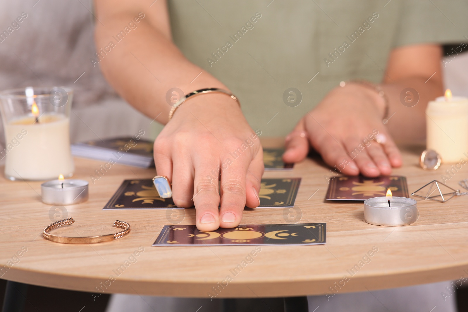 Photo of Soothsayer predicting future with tarot cards at table indoors, closeup