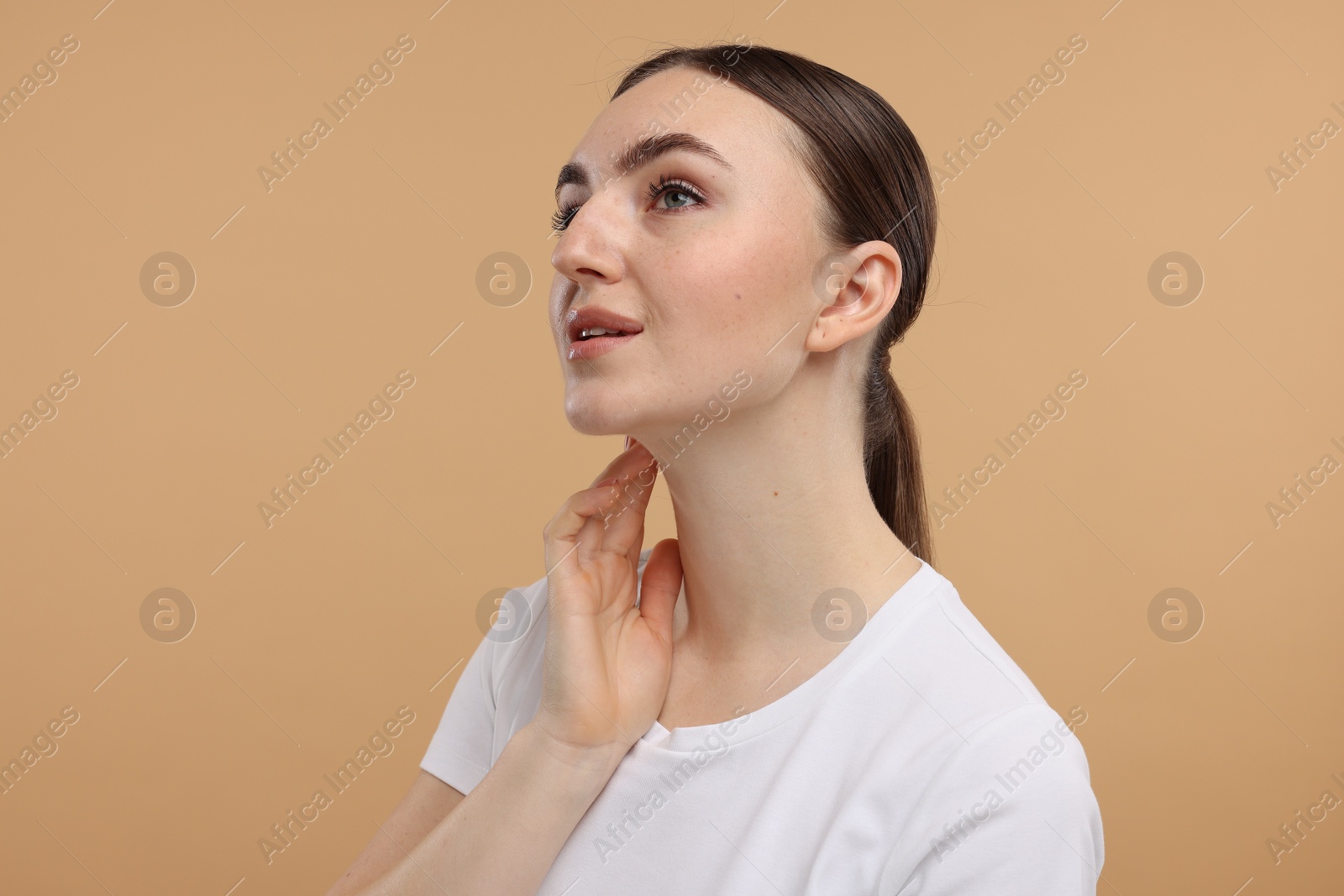 Photo of Beautiful woman touching her neck on beige background