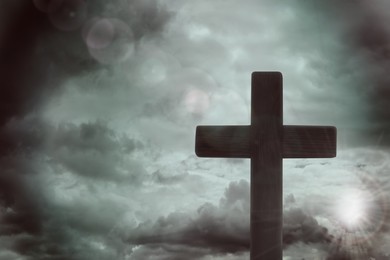 Image of Silhouette of cross against cloudy sky. Christian religion