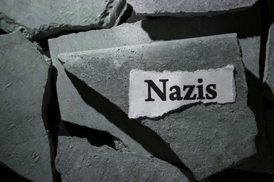 Paper with word Nazis on pieces of concrete, top view