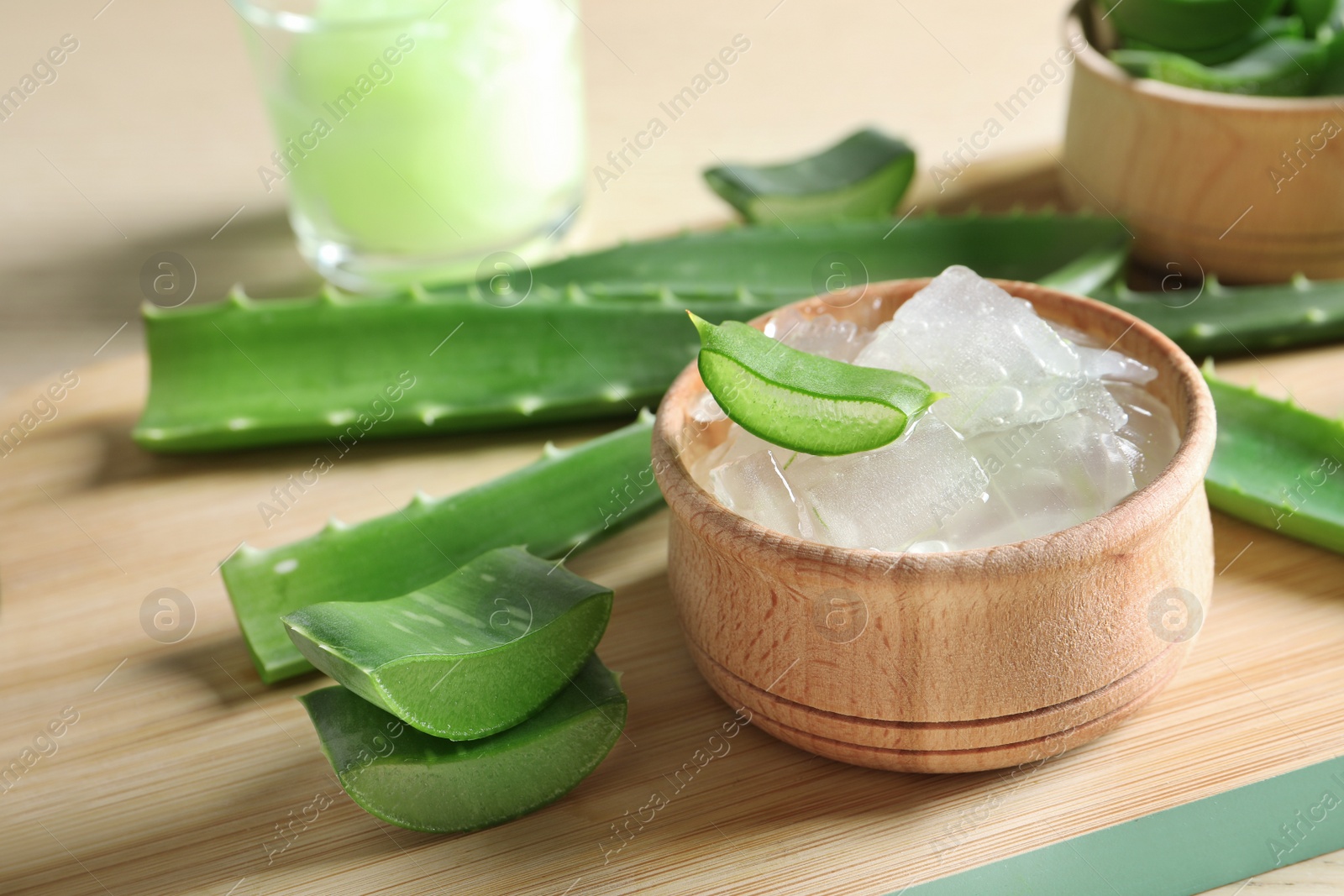 Photo of Bowl with peeled aloe vera and green leaves on wooden board