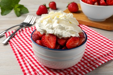 Photo of Bowl with delicious strawberries and whipped cream served on wooden table