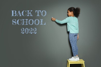 Back to school 2022. African American child with chalk near grey wall