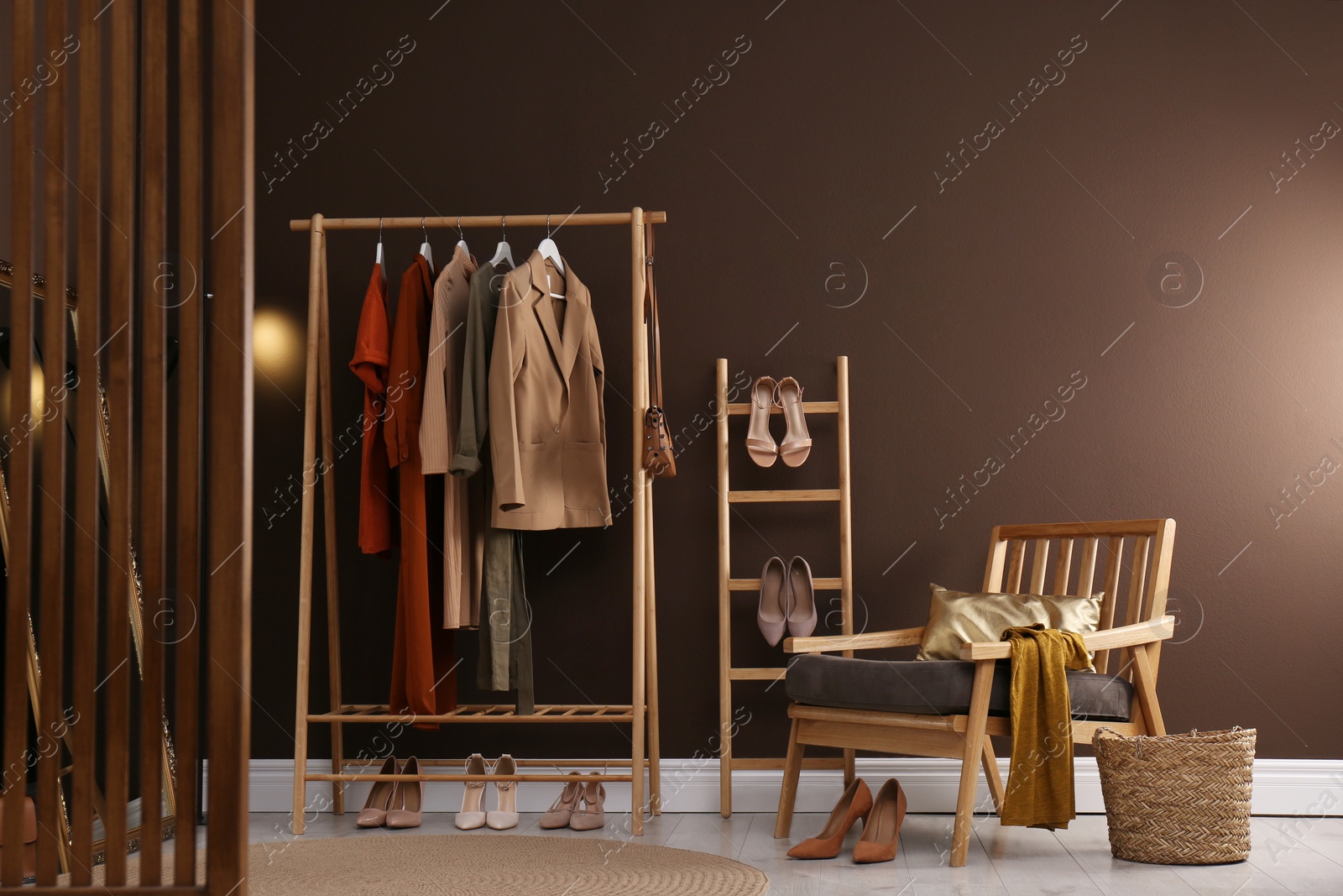 Photo of Modern dressing room interior with clothing rack and comfortable armchair