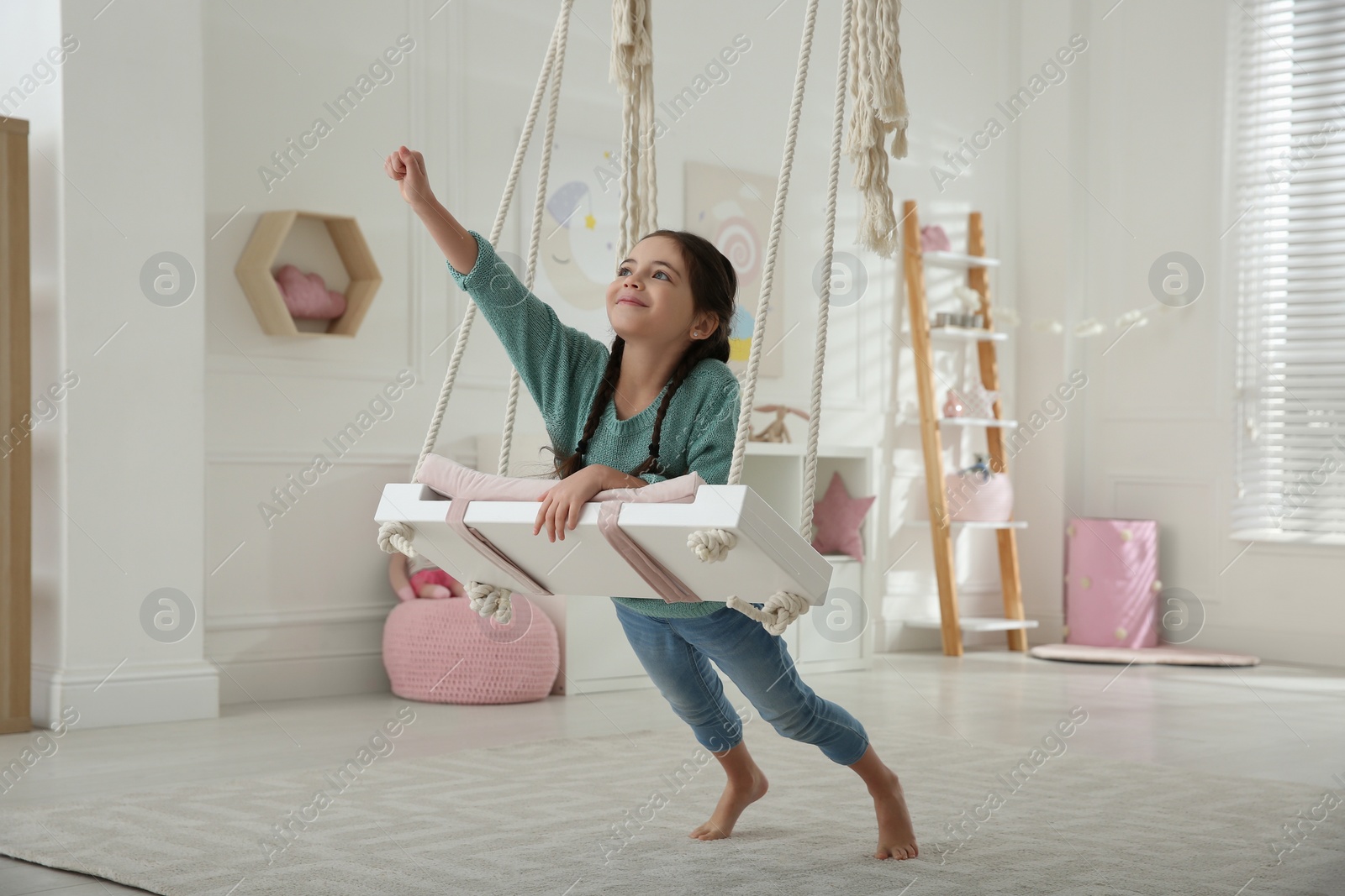 Photo of Cute little girl playing on swing at home