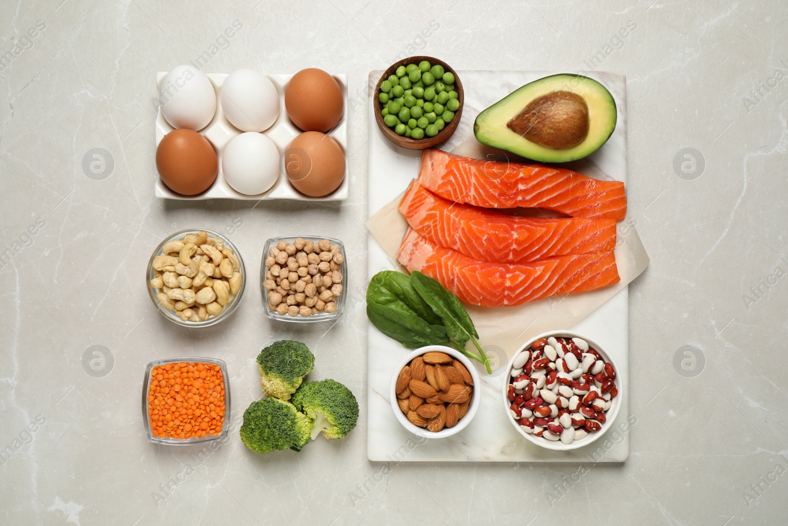 Photo of Products rich in protein on light marble table, flat lay