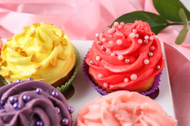 Photo of Delicious cupcake with bright cream on pink fabric, closeup