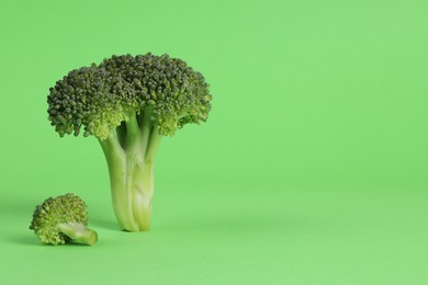 Fresh raw broccoli on light green background, space for text