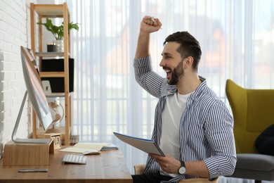 Online test. Happy man studying with computer at home