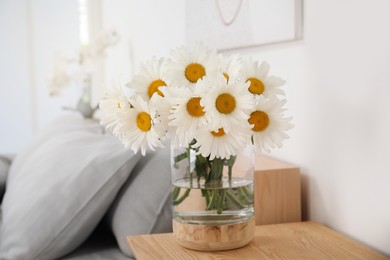Photo of Bouquet of beautiful daisy flowers on wooden table in bedroom