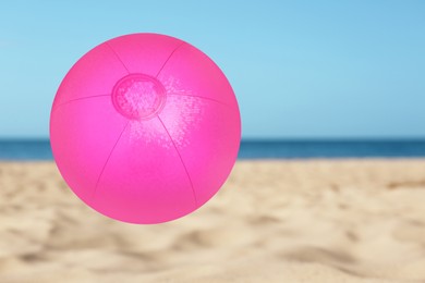 Image of Pink inflatable beach ball and seascape on background