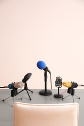 Photo of Microphones on light grey table in conference hall. Journalist's work