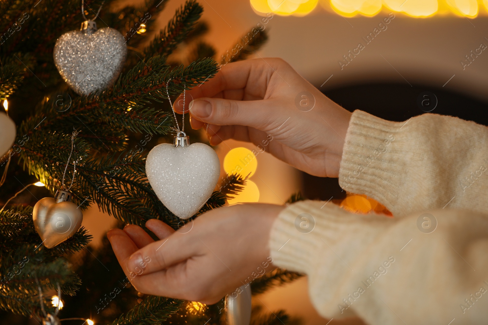 Photo of Woman decorating Christmas tree at home, closeup