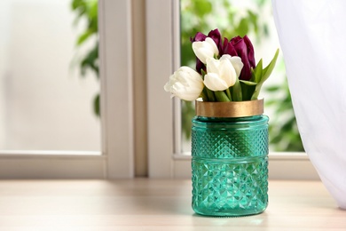 Beautiful tulips in vase on window sill. Space for text