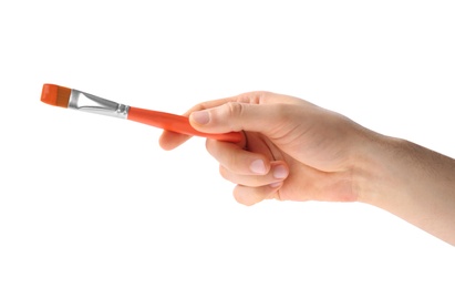 Young man holding brush with color paint on white background, closeup