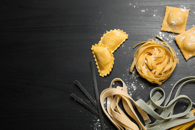 Photo of Flat lay composition with different types of pasta on black wooden table