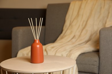 Photo of Aromatic reed air freshener on wooden table indoors, space for text