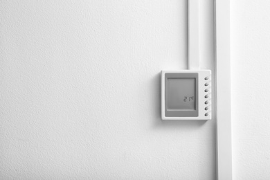 Photo of Modern thermostat and space for text on white wall. Heating system