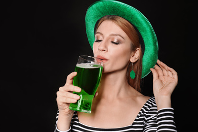 Photo of Young woman with green beer on black background. St. Patrick's Day celebration