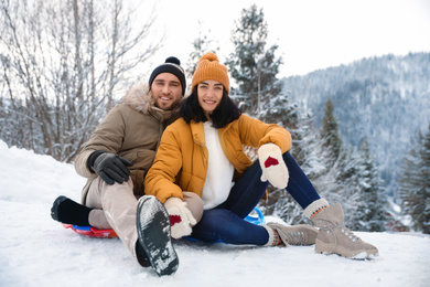 Photo of Happy couple sliding on snowy hill. Winter vacation