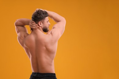 Muscular man on orange background, back view and space for text. Sexy body