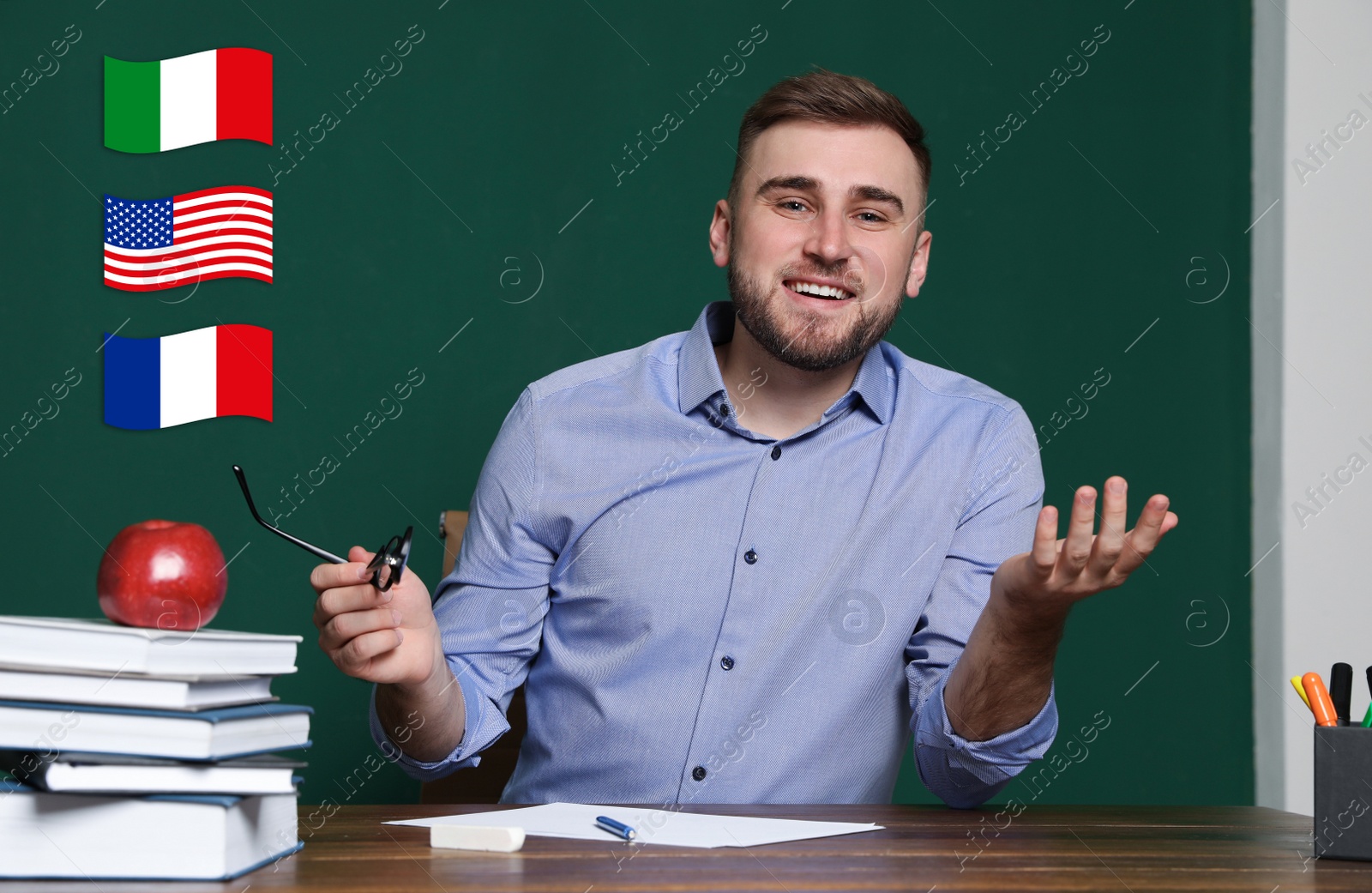 Image of Portrait of foreign languages teacher at wooden table and different flags green chalkboard