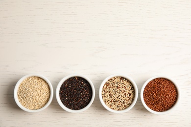 Photo of Flat lay composition with different types of quinoa and space for text on white wooden background