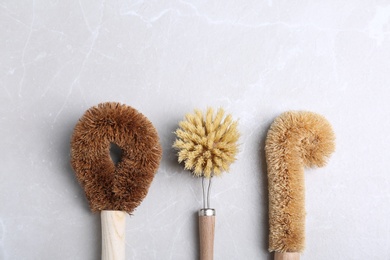 Photo of Cleaning brushes for dish washing on grey table, flat lay