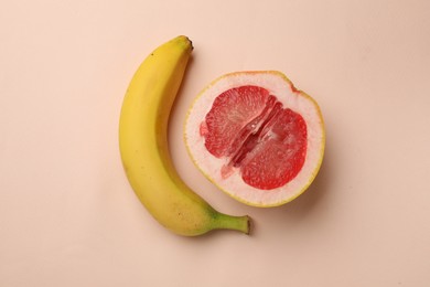 Photo of Banana and half of grapefruit on beige background, flat lay. Sex concept