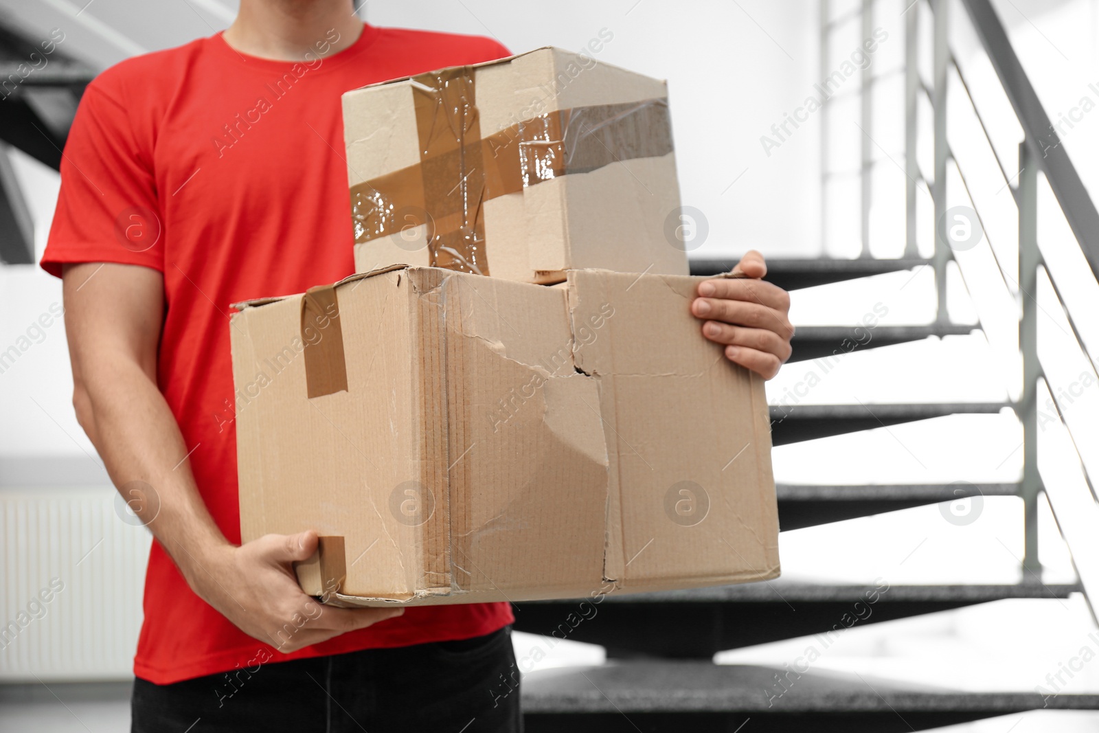 Photo of Courier with damaged cardboard boxes indoors, closeup. Poor quality delivery service