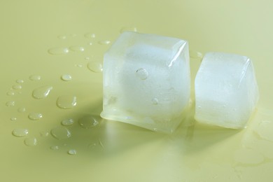 Crystal clear ice cubes on yellow background, space for text