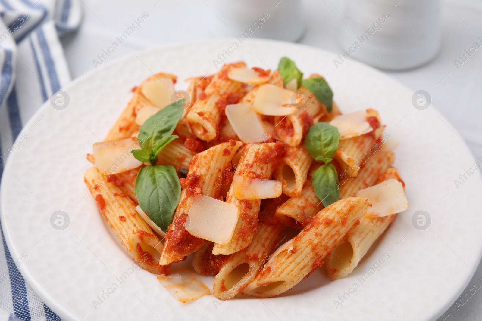 Photo of Tasty pasta with tomato sauce, cheese and basil on table, closeup