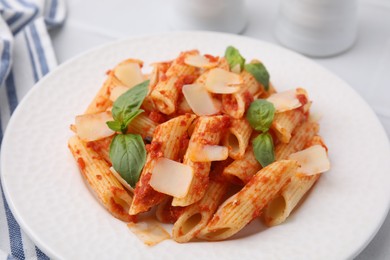 Tasty pasta with tomato sauce, cheese and basil on table, closeup